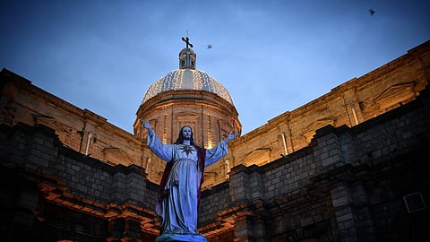 The church is distinguished by three large blue and white cross-topped domes illuminated at night